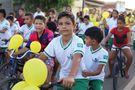 Fahrradfahrender Schüler der Kinderhilfe Brasilien blickt in die Kamera. Im Hintergrund eine Menge weiter radelnder Kinder