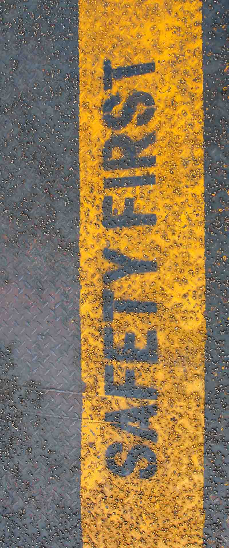 "Safety first" Schriftzug gelb hinterlegt auf Beton