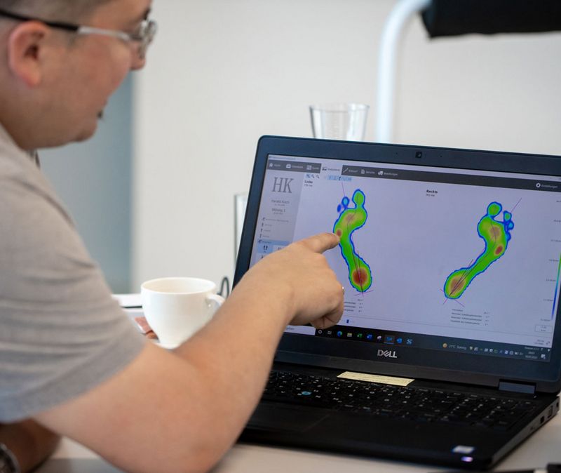 Abbildung eines Mannes, der am Computer eine Abbildung von Füßen analysiert.