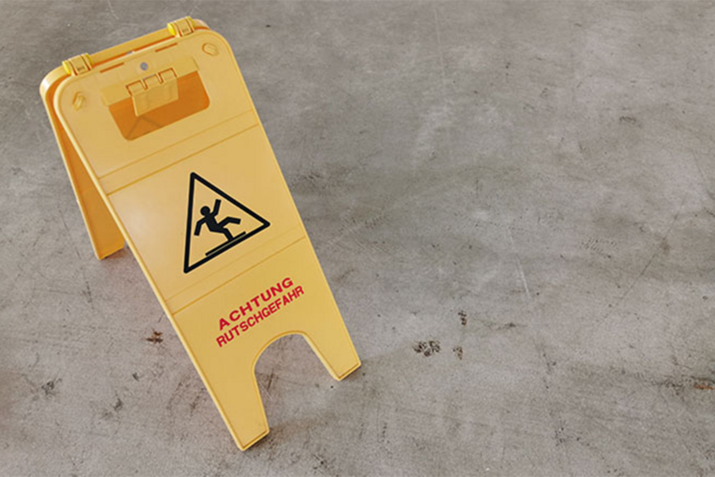 Gelber Warnaufsteller Achtung Rutschgefahr auf Betonboden
