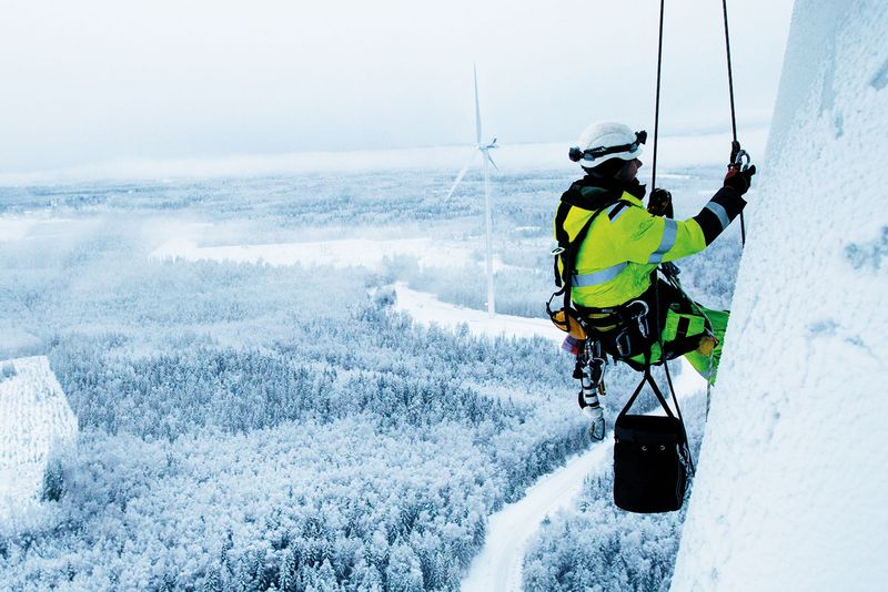 Arbeiter in Schutzbekleidung in winterlicher verschneiter Umgebung während Instandhaltungsarbeiten bei Skiliftanlage