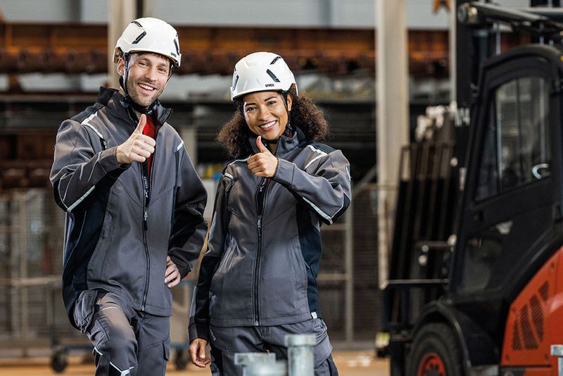 Mann und Frau, beide in grau gekleidet, tragen Uvex-Helme mit Mips-Sicherheitssystem