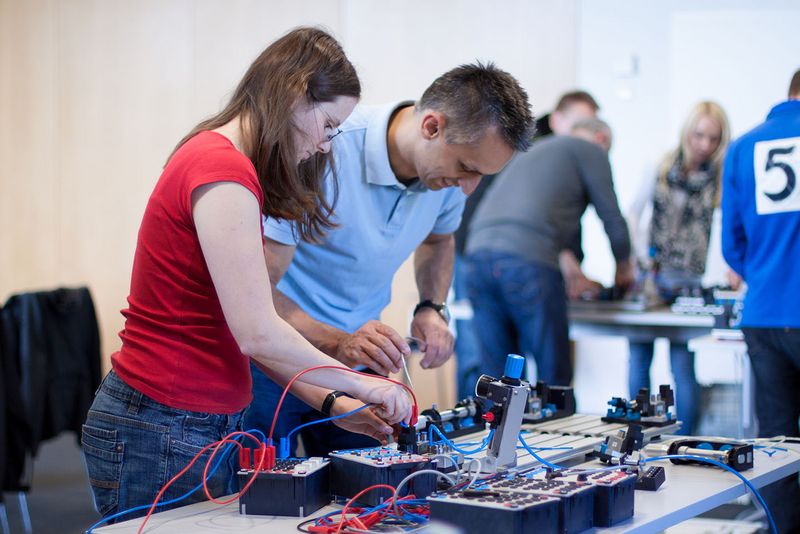 Frau in rotem T-Shirt und Mann in blauem T-Shirt während Schulung zum Thema Elektrotechnik