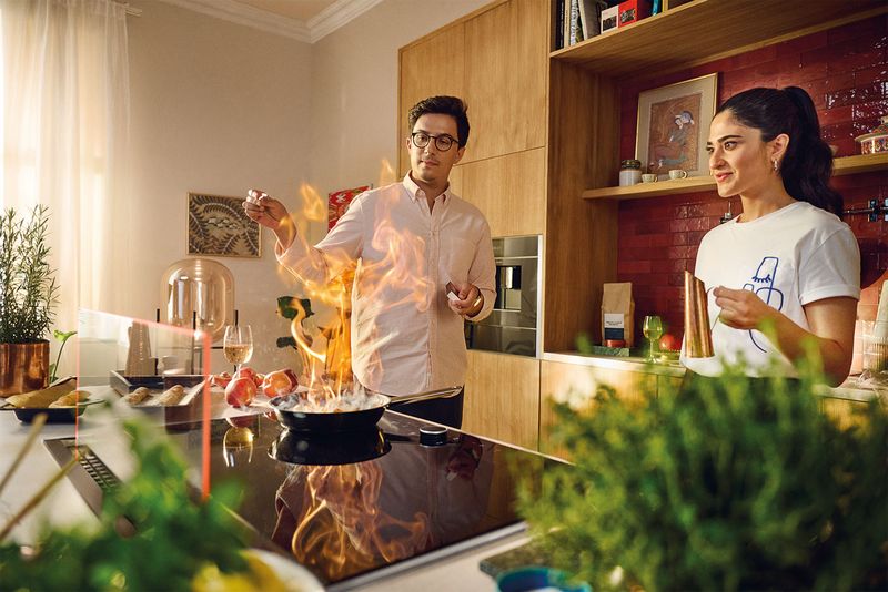 Mann und Frau in Küche flambieren Speise 