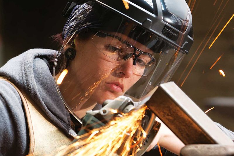 junge Frau in Industriebetrieb arbeitet mit Schutzbrille