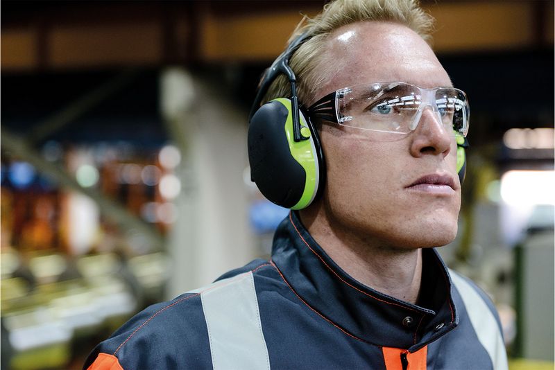 Arbeiter in Industrieumgebung trägt Gehörschutz und eine Schutzbrille