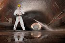 Arbeiter in Schutzbekleidung von DuPont versprüht in Tunnel Flüssigkeit